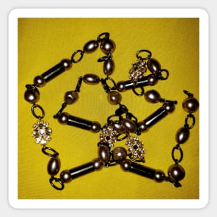 Pearls, black beads, and chains, on a deep yellow background Sticker